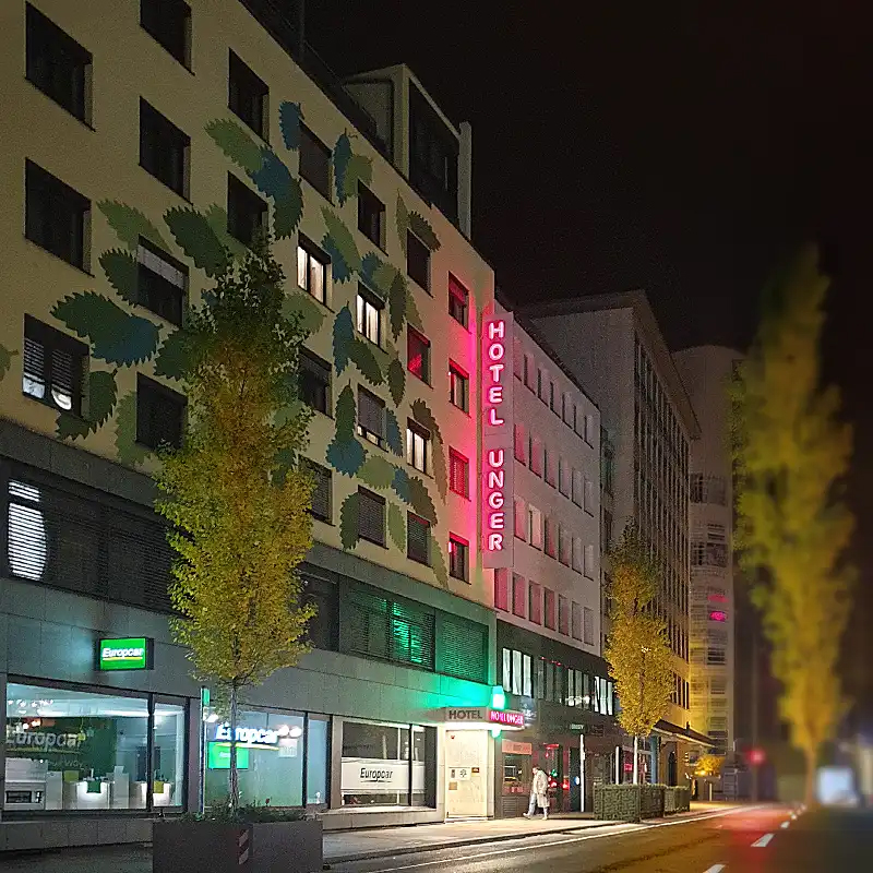 Hotel Unger Eingang bei Nacht. Rote Leuchtbuchstaben.